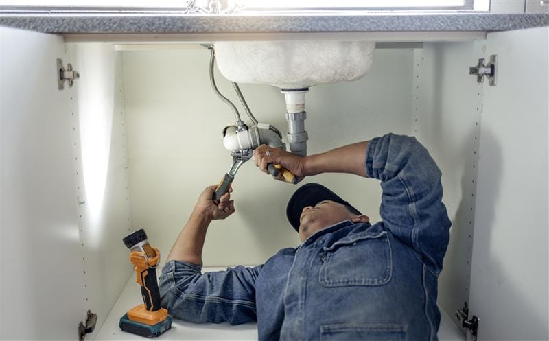 Plumber repairing pipes beneath a bathroom sink in Stevenson Ranch